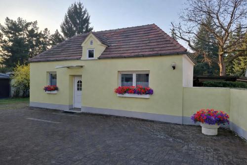 a small yellow house with two windows and flowers at Haus-Sonnenschein - Lausitzer Seenland - Senftenberger See in Senftenberg