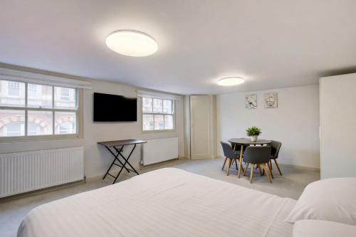a room with a bed and a table and a tv at Stylish 2BR Apartment in Leicester Square in London