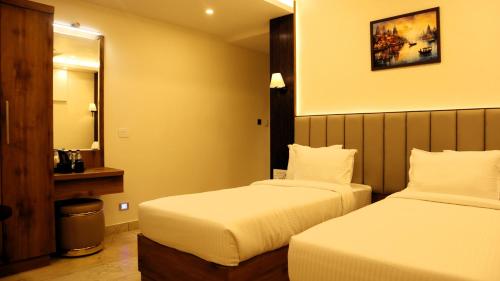 a hotel room with two beds and a mirror at Narmada Residency in Hubli