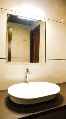 a sink in a bathroom with a mirror at Narmada Residency in Hubli