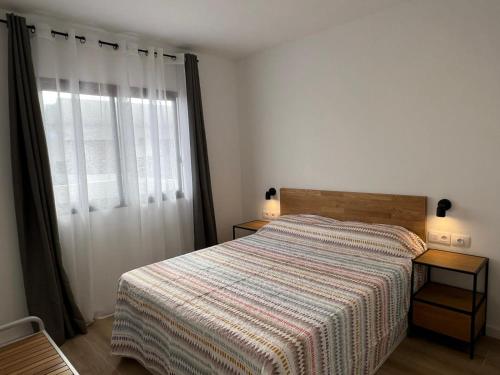 a bedroom with a bed with a striped blanket and a window at Dunasol 311 in Corralejo