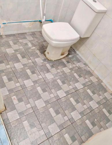 a bathroom with a toilet and a tiled floor at At Home สระบุรี in Sara Buri