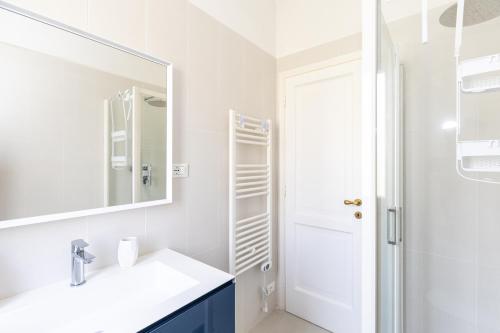 a white bathroom with a sink and a mirror at La Caletta Di Luce in Lerici