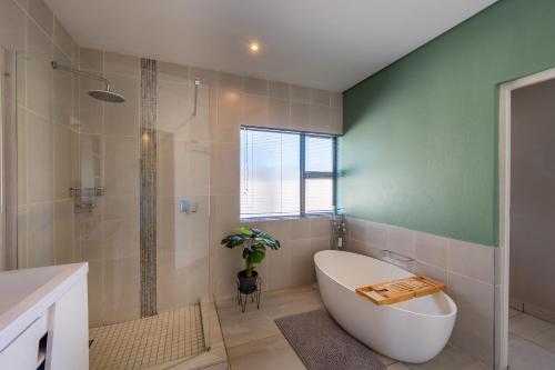 a bathroom with a tub and a glass shower at Khaya Elihle Guest House in Hazyview