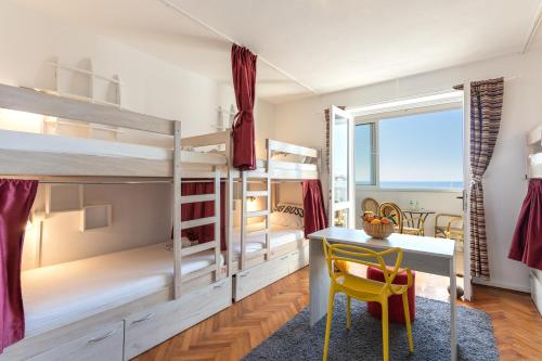 a bedroom with bunk beds with a desk and a table at Hostel Casa La Cha in Novalja