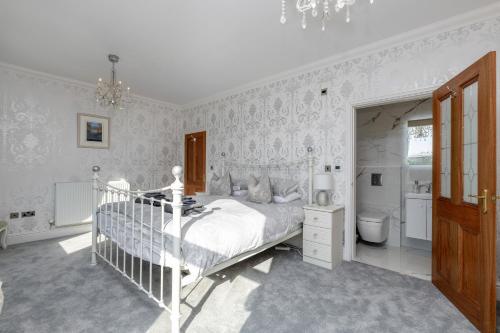 a white bedroom with a bed and a bathroom at Snowdonia View in Llanfairpwllgwyngyll