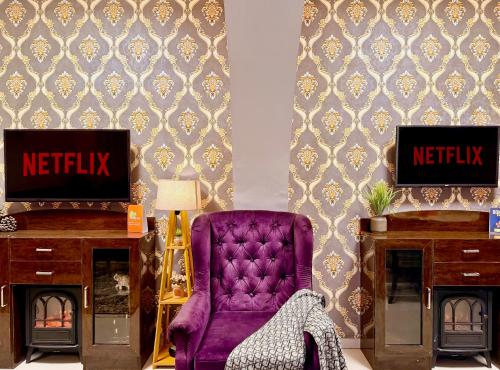 a living room with a purple chair and a tv at The Bay Leaf Resort in Shimla