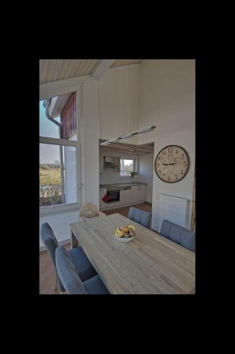 a dining room table with chairs and a clock on the wall at Ferienhaus Luan in Nordhorn
