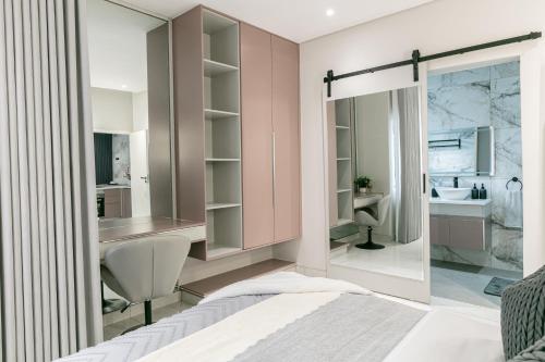 a bedroom with a bathroom with a sink and a mirror at Ditsametse Luxe Suites in Gaborone