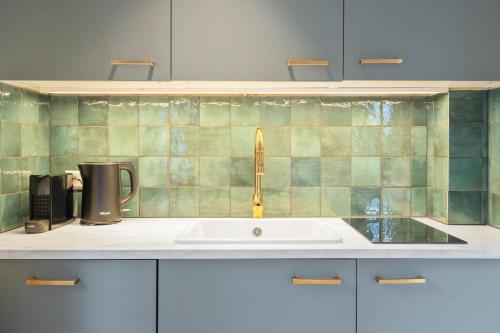 a kitchen with a sink and a green tiled wall at Studio Oak & Studio Linde in Aerdenhout