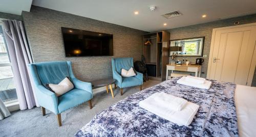 a bedroom with a bed and two chairs and a television at The Lord Street Hotel; BW Signature Collection in Southport