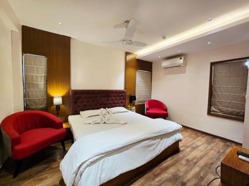 a hotel room with a bed and two red chairs at Hotel Akashdeep in Kolkata