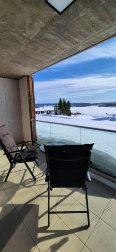 two chairs on a balcony with a view of the water at Flat With Lake View In Sjusjøen in Sjusjøen