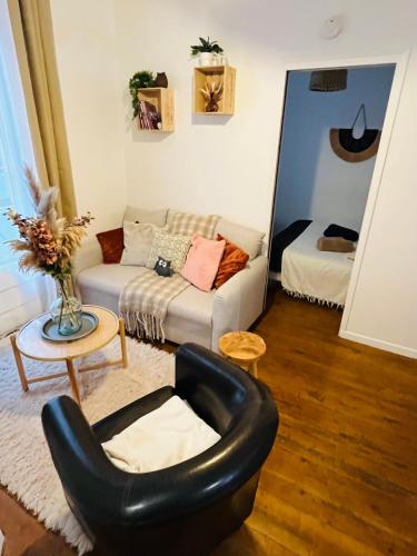 a living room with a black chair and a couch at Le Petit Millésime - Homillesime in Dijon