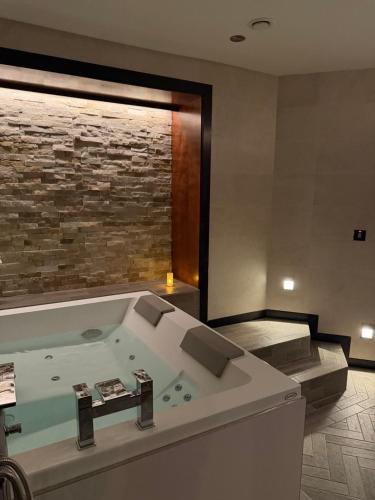 a bathroom with a bath tub with a stone wall at Lochgreen House Hotel & Spa in Troon