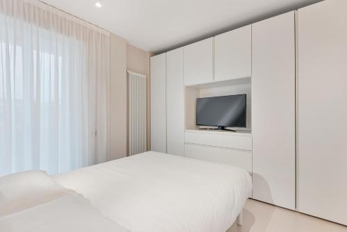 a white bedroom with a bed and a tv at Magnolia Studio Appartamento Marina di Carrara in Marina di Carrara
