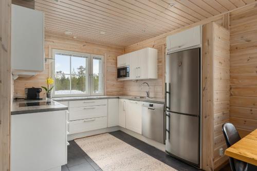 a kitchen with white cabinets and a stainless steel refrigerator at Skicamp 3 - Modern 3BR Villa in Pyhätunturi in Pyhätunturi
