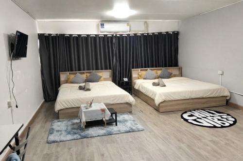 a bedroom with two beds and a television in it at popular condo c5 แม่ตัง in Thung Si Kan