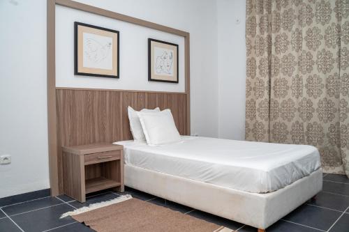 a bedroom with a white bed with a nightstand and a bed sidx sidx sidx at Rassyl Résidence in Jendouba