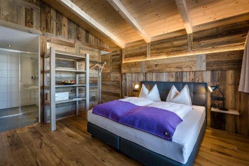 a bedroom with a bed and a wooden wall at almlust - hotel, apartments, chalets in Flachau