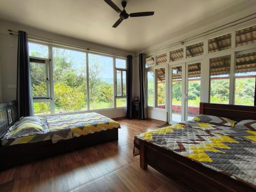 a bedroom with two beds and large windows at Tayra - The Glass Villa in Somvārpet