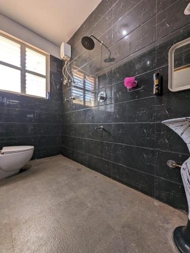 a bathroom with a black tiled wall at Tayra - The Glass Villa in Somvārpet