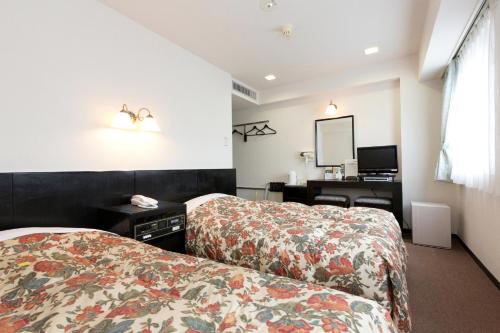 a hotel room with two beds and a desk at Plaza Hotel Fujinoi in Hita