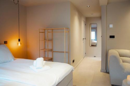 a bedroom with a white bed and a chair at Studio Strandkasteel, Free parking in Zandvoort