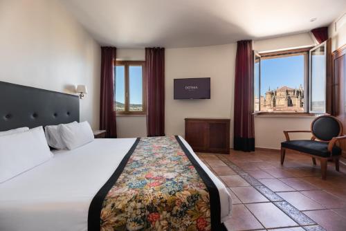 a hotel room with a bed and a chair at Dorma Alfonso VIII in Plasencia