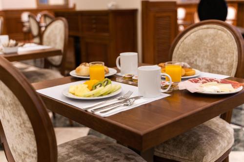 a wooden table with plates of food and orange juice at Dorma Alfonso VIII in Plasencia