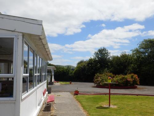 a white building with a window and a yard at Thomas's Catlins Lodge and Camp Ground in Owaka