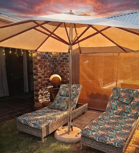a patio with two chairs and an umbrella at Romaic Guesthouse Welkom in Welkom