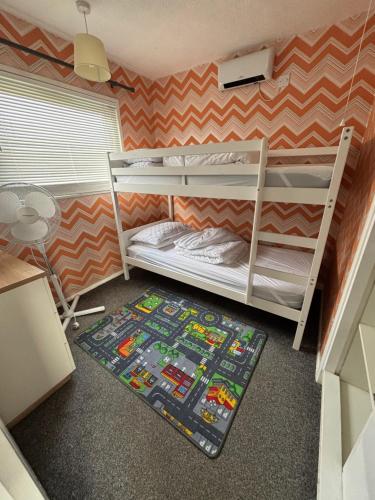 a room with two bunk beds and a rug at 58, Two bed chalet on Sund0wner Holiday Park - Sleeps 4, pet friendly - Free WiFi plus electricity all included - Entertainment options close by in Hemsby