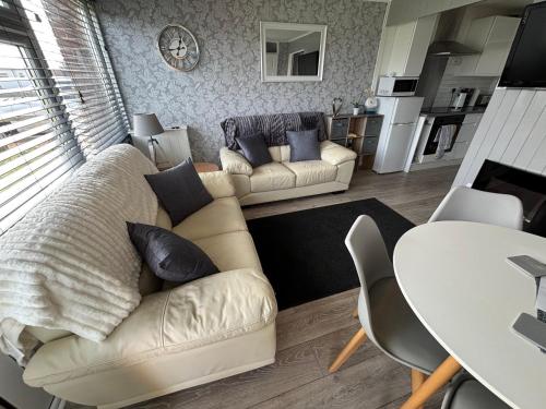 a living room with a couch and a table at 58, Two bed chalet on Sund0wner Holiday Park - Sleeps 4, pet friendly - Free WiFi plus electricity all included - Entertainment options close by in Hemsby