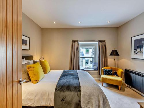 a bedroom with a large bed and a yellow chair at 3 Bed in Leyburn oc-76395 in Askrigg
