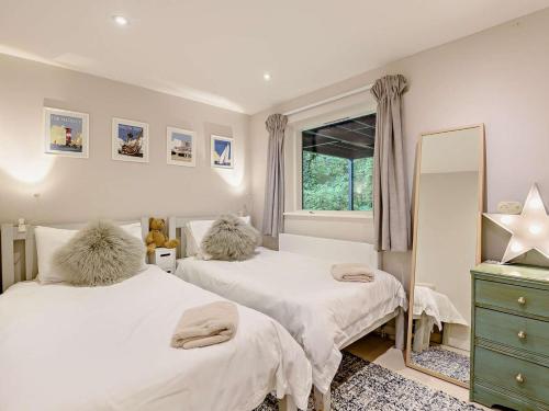 a bedroom with two beds and a mirror and a window at 3 Bed in Brockenhurst oc-47431 in Beaulieu