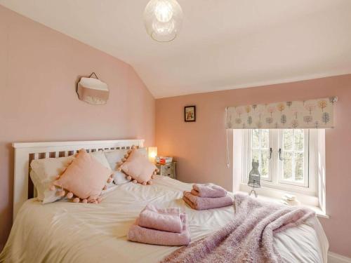 a bedroom with a bed with pink pillows and a window at 2 Bed in Otley oc-75268 in Lindley