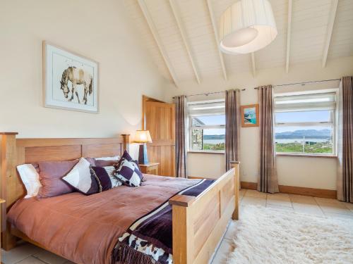 a bedroom with a bed and two windows at Diamond Cottage in Ballyconneely