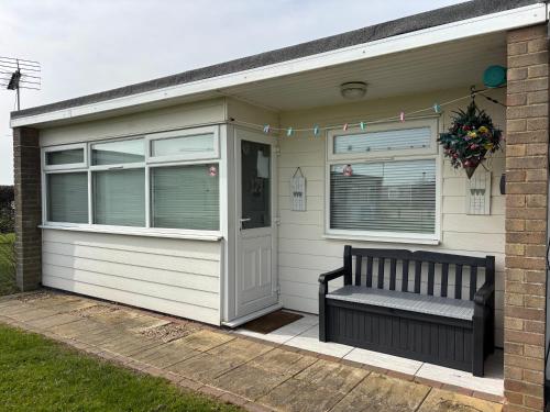 a bench sitting outside of a house with a window at 179, Two bed chalet on Sund0wner Holiday Park - Sleeps 4, free WiFi, sorry no pets - entertainment options close by in Hemsby