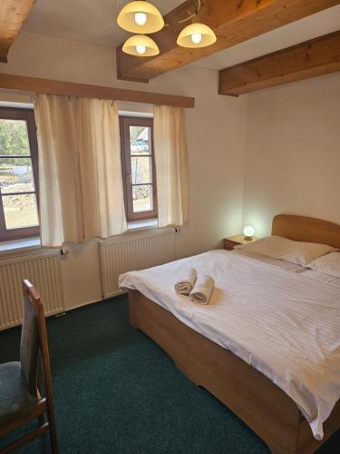 a bedroom with a bed and two windows at Penzion Pupík in Modrava