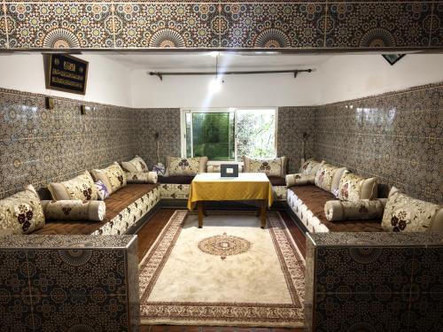 a living room with a couch and a table at Chambres et table d'hôtes Caracalla in Douar Doukkara