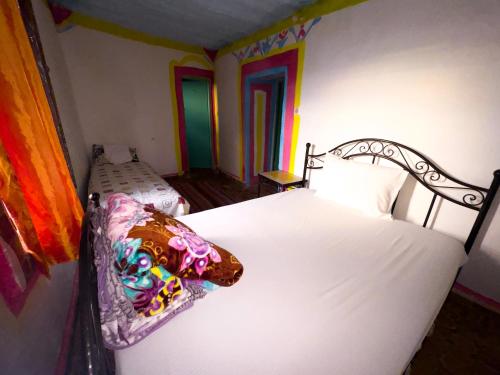 a bedroom with a white bed with a pillow on it at Chambres et table d'hôtes Caracalla in Douar Doukkara