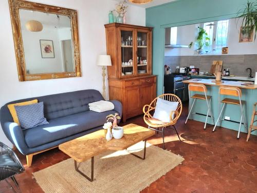 a living room with a blue couch and a kitchen at La Bycoque, maison 2 chambres au calme in Thomery