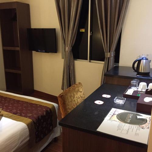 a hotel room with a bed and a desk at Hotel & Apartment Ambassador 3 in Labuan