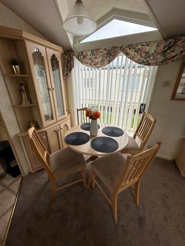 a dining room with a table and chairs and a window at Luxury Caravan Coastfields Holiday Village in Ingoldmells