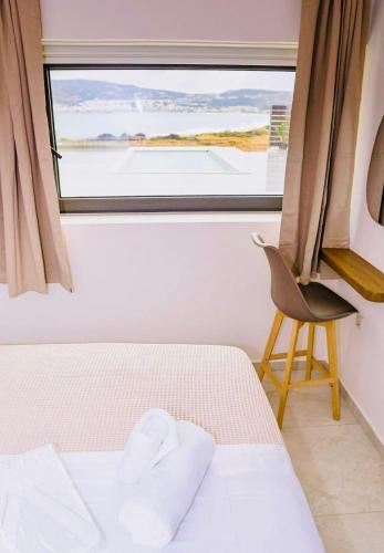 a bedroom with a bed and a window with a chair at Relaxury Villa III in Karpathos