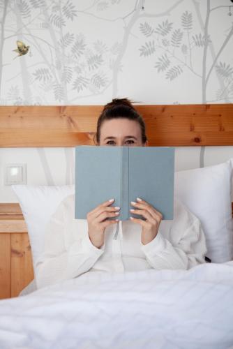 a man laying in bed reading a book at Hotel Vierjahreszeiten in Flachau