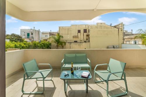 a patio with chairs and a table and a bottle of wine at Tenuta VillaMar in Cursi