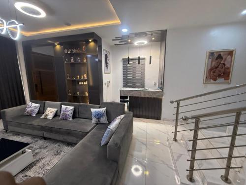 a living room with a gray couch and a bar at Le ChriShol in Ikuata