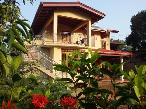 a house with a balcony and red flowers at Sigiriya Peacock Homestay in Sigiriya